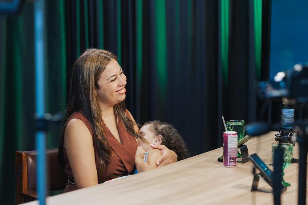 Fabi em podcast com a filha no colo
